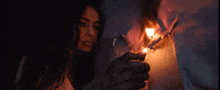 a woman is lighting a lantern with a lighter in a dark room .