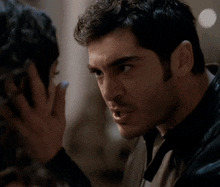 a man and a woman are kissing and the woman is covering her face with her hand .