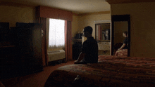 a man sits on a hotel bed in front of a mirror