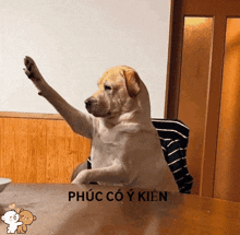 a dog is sitting at a table with its paw up and the words phúc co y kien written on the bottom