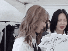 a woman is holding a piece of paper with a signature on it that says ' miss '