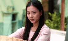 a woman in a pink shirt is sitting on a wicker table .