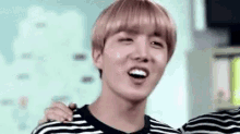 a young man in a striped shirt is smiling and laughing .