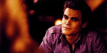 a man in a purple shirt is smiling while looking at another man .