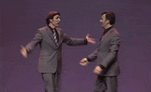 a man in a suit and tie is dancing on stage .