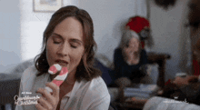 a woman is eating a candy cane from a hallmark countdown to christmas movie