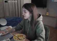 a woman sits at a desk with a bowl of food in front of her and a screen that says csc on it