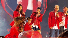 a group of people in red jackets and ties singing into microphones on a stage