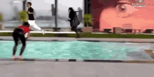 a woman is jumping into a swimming pool while a man watches .