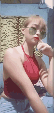 a woman wearing sunglasses and a red top is looking at the camera