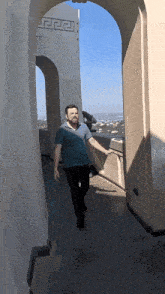 a man in a blue shirt walks through a doorway