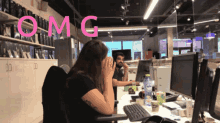a woman sits at a desk with her hands on her face and the word omg above her