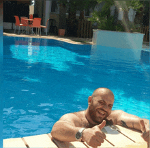 a man in a swimming pool gives a thumbs up sign