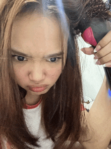 a woman brushes her hair while making a funny face