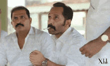 a man with a mustache is smoking a cigarette while another man looks on ..