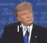 donald trump is wearing a suit and tie and making a funny face while speaking into a microphone .