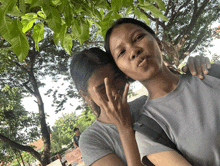 two girls are posing for a picture with one wearing a gray shirt that says asics