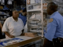 a man in a blue uniform is talking to a woman at a counter in a store