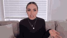 a woman is sitting on a couch with her hands out