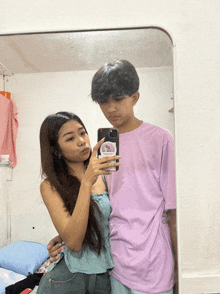 a man in a purple shirt is taking a selfie with a girl in a blue top