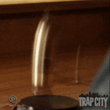 a man in an orange shirt is standing in front of a trap city poster