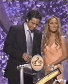 a man in a suit and tie is standing next to a woman in a dress behind a podium .