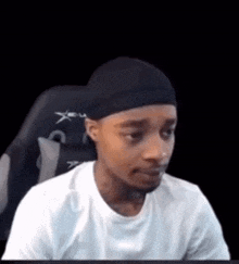 a man is sitting in a chair wearing a headband and a white shirt .