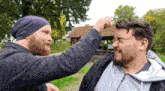 a man wearing a purple beanie is punching another man 's head