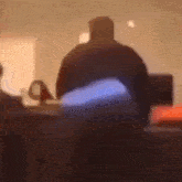 a blurry picture of a man sitting in a chair in a dark room .