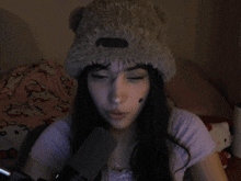 a woman wearing a teddy bear hat talks into a microphone in a dark room