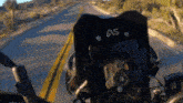 a person is riding a motorcycle down a road with a black bag that says " as " on it