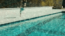 a man is jumping into a swimming pool with his shirt off