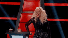 a woman is dancing in front of a red chair on a stage .