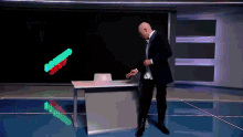 a man in a suit is standing in front of a desk with a green and red sign that says ' a ' on it