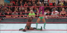 a man is kneeling down in a wrestling ring while a woman is standing in the corner .