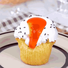 a cupcake with white frosting and orange sauce on it