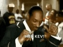 snoop dogg is wearing a suit and tie and holding a microphone in front of him .