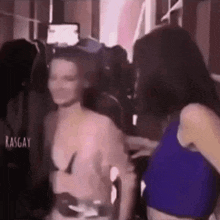 a woman in a blue top is standing next to another woman in a crowd .