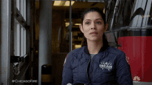 a woman in a chicago fire department jacket stands in front of a red fire truck
