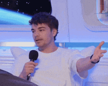 a man in a white shirt is holding a microphone and talking into it