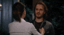 a man and a woman are standing next to each other in front of a door .