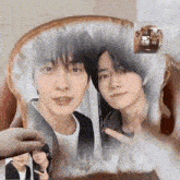 two young men are sitting next to each other on a chair .