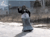 a woman in a long skirt is dancing on a street .