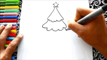 a person is drawing a christmas tree with markers