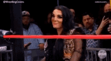 a woman is standing in a wrestling ring with a champion 's belt .