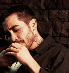 a man with a tattoo on his neck has his hand on his chin
