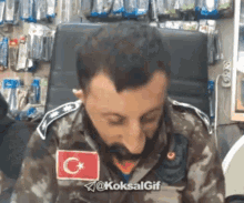 a man in a military uniform with a flag on his chest is sitting in a chair .