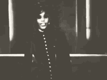 a black and white photo of a woman in a black coat dancing .