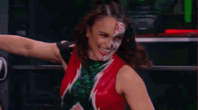 a woman with face paint on her face is flexing her muscles while wearing a red and green outfit .