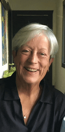 a woman wearing a black shirt and a silver necklace smiles for the camera